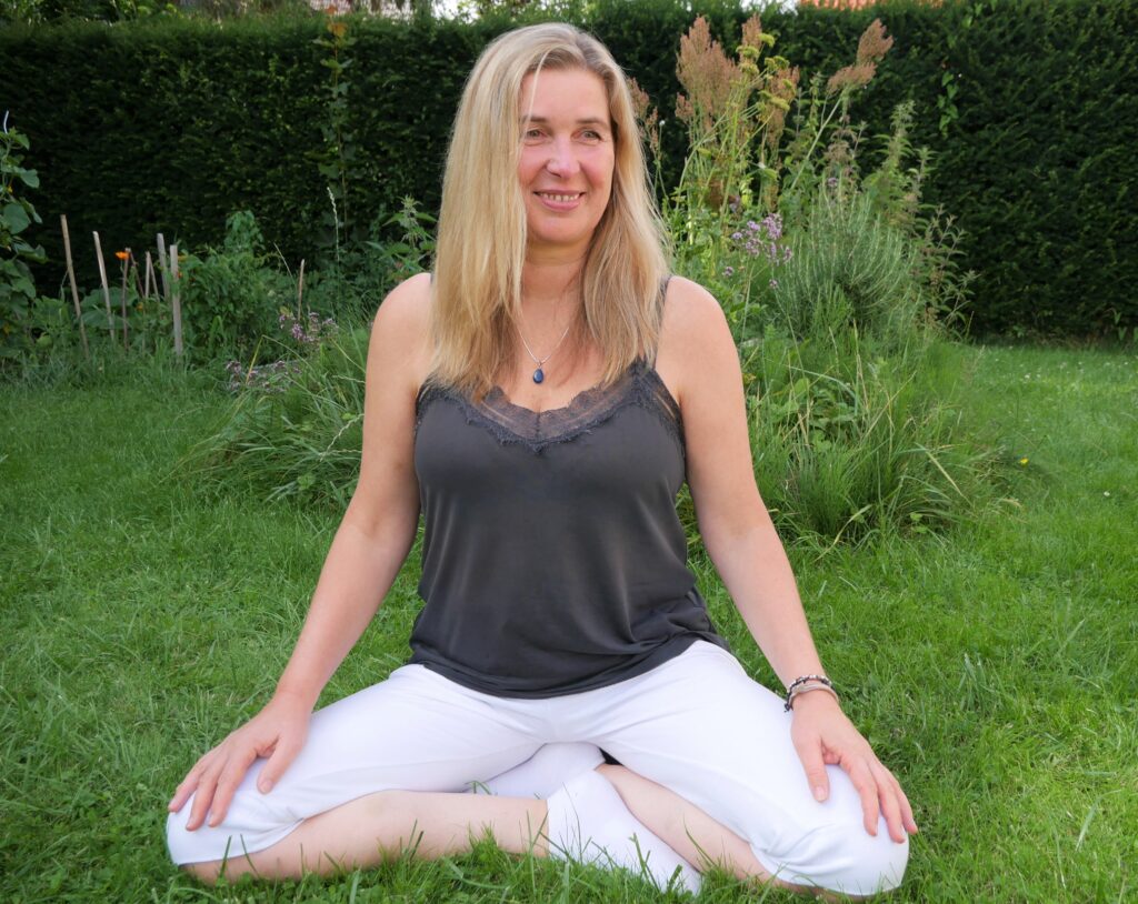 Ulrike im Sommer, sitzend im Garten in Yogapose